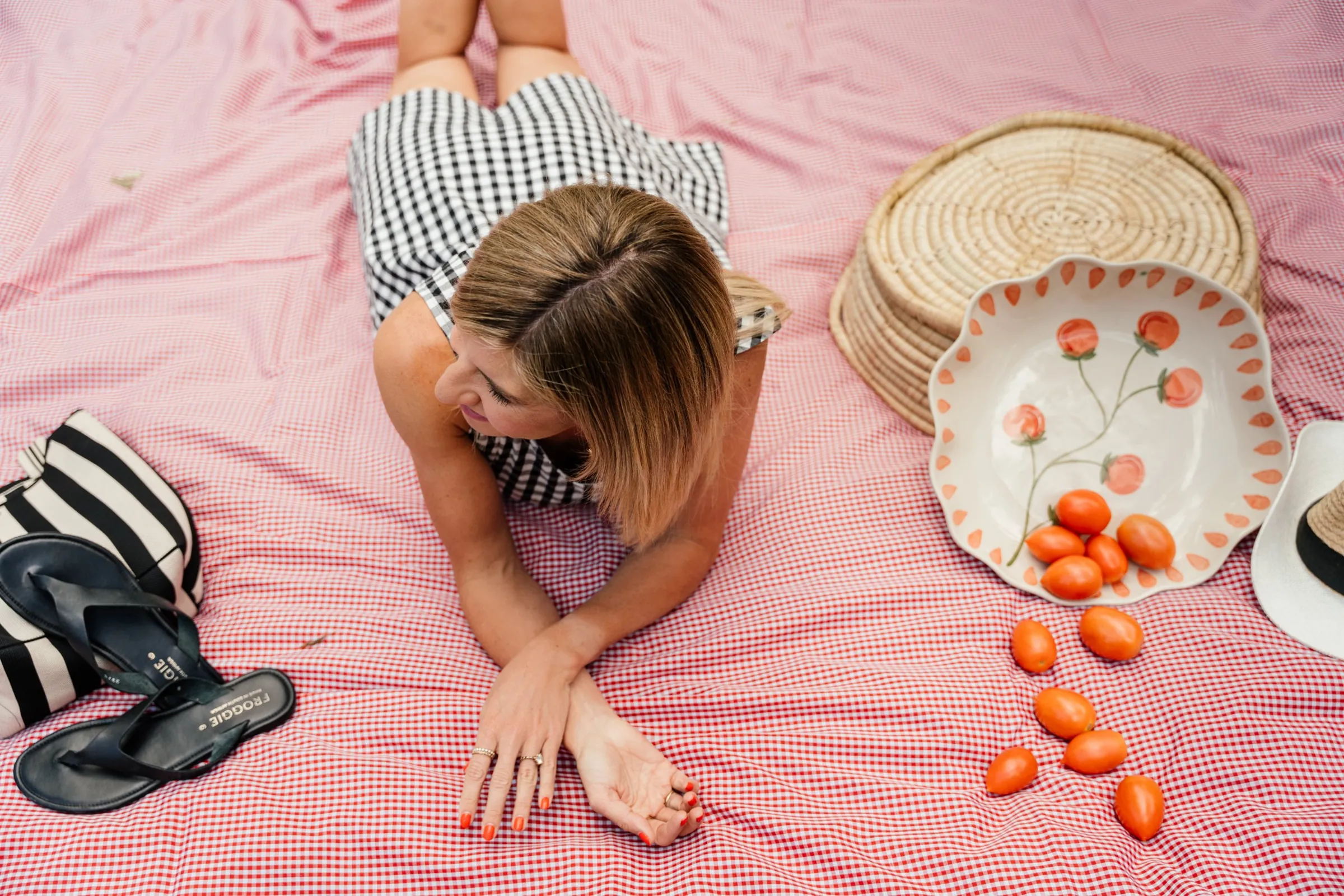 Jeanine lying on a pink picnic blanket with a bowl of oranges